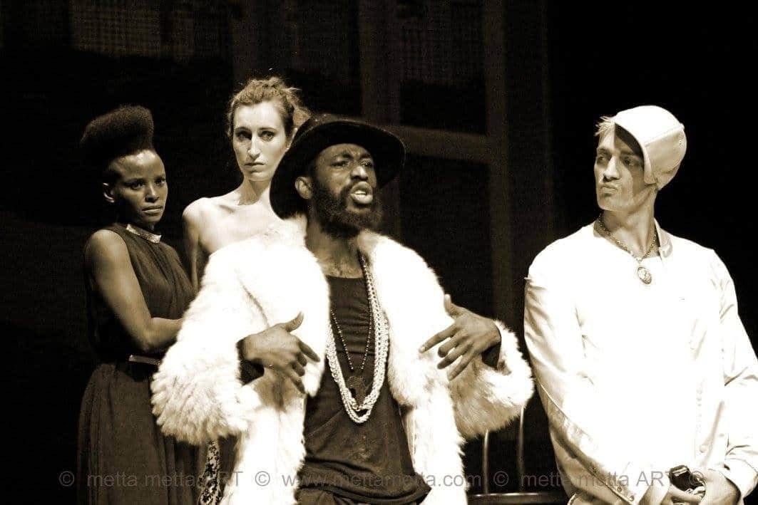 Sepiafarvet trioscene fra The Merchant of Venice med en central figur i pelsfrakke flankeret af to andre.