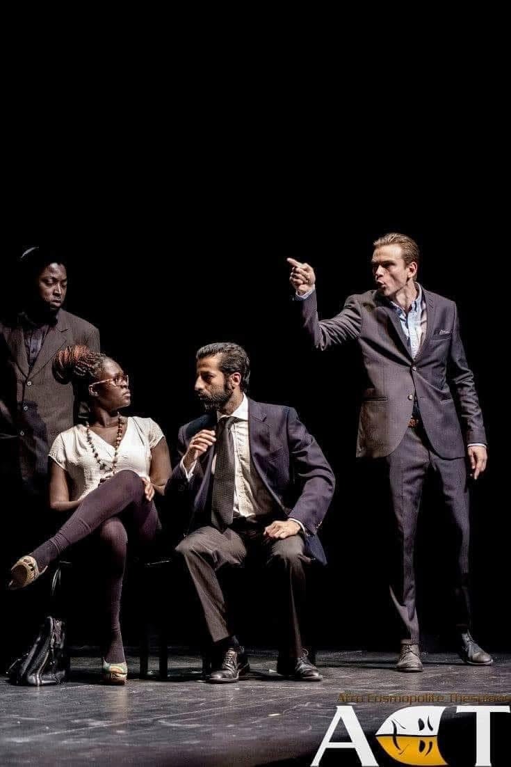 Retssalslignende konfrontation fra The Merchant of Venice, hvor en jakkeklædt mand peger under en anspændt udveksling.